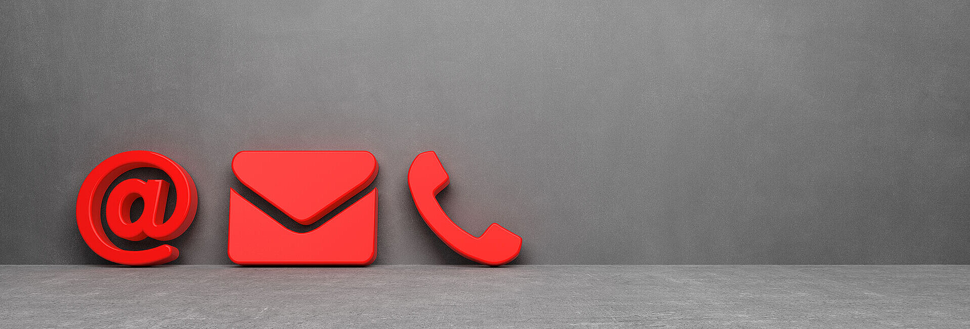 Ein rotes @-Zeichen, ein Briefumschlag und ein Telefonhörer als Symbol vor einer grauen Wand